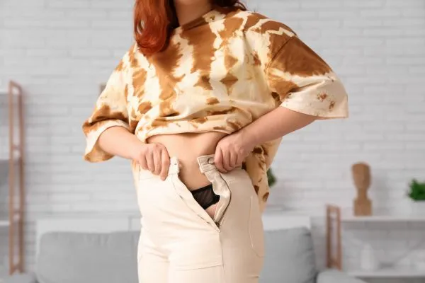 Image of woman trying to do her trousers up after pregnancy weight gain Wolverhampton